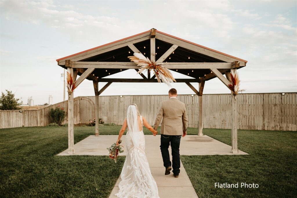 The Cornerstone Ranch Events Center in Amarillo, TX, established in 2014, is a family-owned and operated wedding venue. Bride and groom walking toward the wedding ceremony site at Cornerstone Ranch Wedding Venue Amarillo Texas