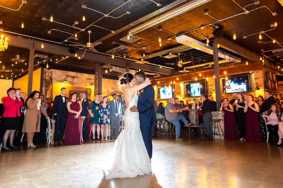 Bride and groom first dance while wedding guests look on and enjoy the rustic vibes at this Milwaukee wedding venue