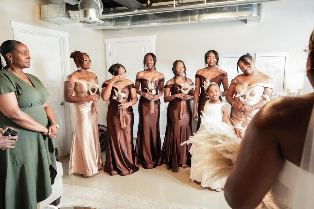 The bridesmaids get emotional as they see the bride during a first look at their industrial chic wedding venue near Winston Salem in Kernersville NC