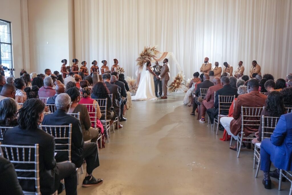 Bride and groom exchanging vows in front of 200 weddings guests at an indoor ceremony at The Event at Two Ten in Kernersville, North Carolina