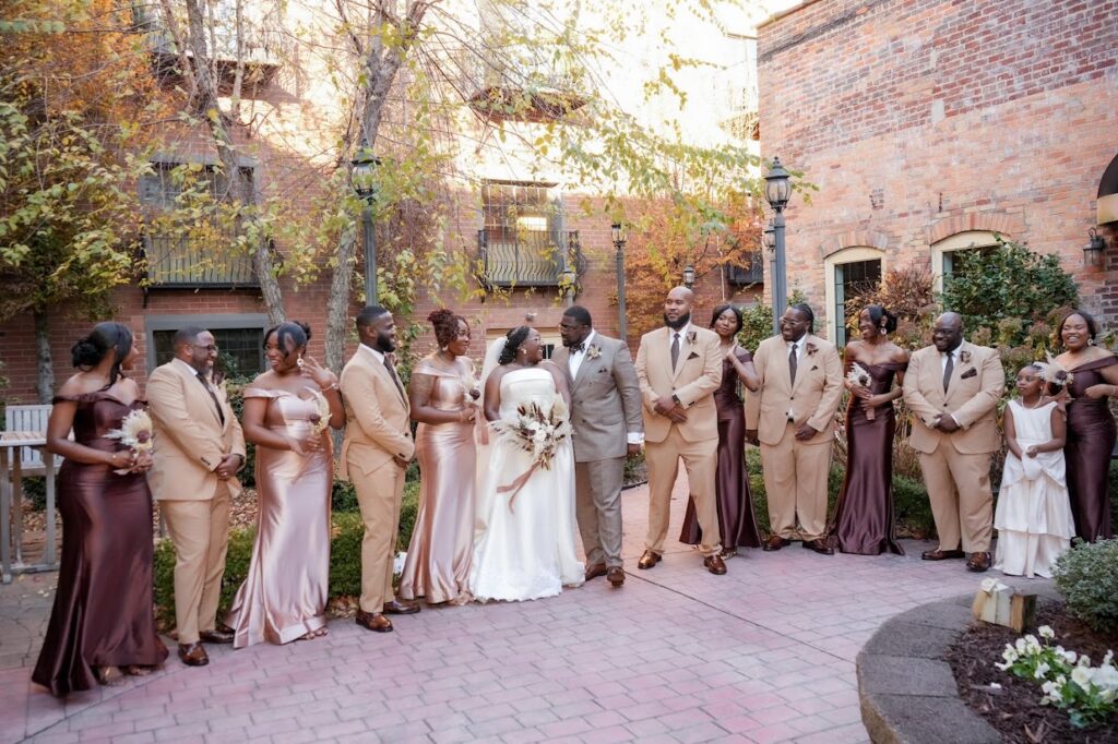 Wedding party dressed beautiful formal wear pose with the bride & groom in a garden courtyard at The Event at Two Ten wedding venue near Winston Salem in Kernersville NC