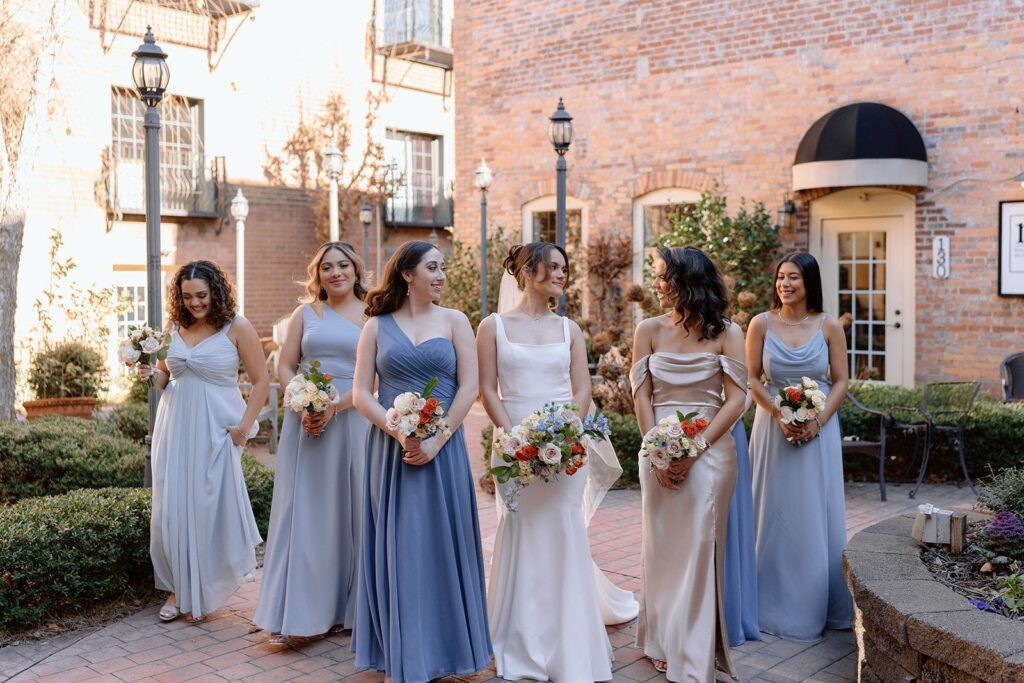 Bride & bridesmaids wearing blue as they post for garden courtyard photos before the wedding at The Event at Two Ten near Winston-Salem