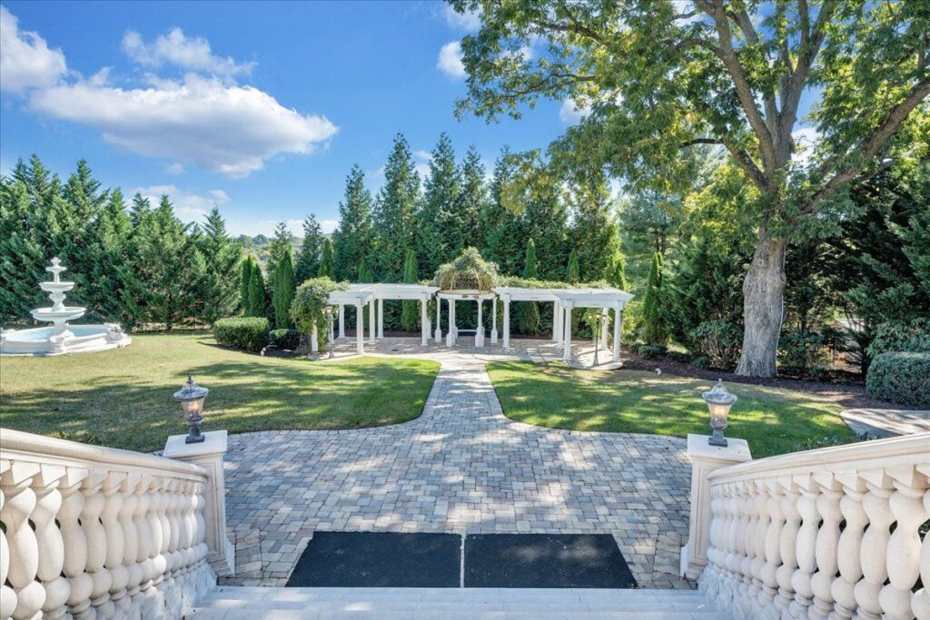 Grand staircase leading to the outdoor garden wedding ceremony site with elegant pavilion, fountain, paved walkways and mature trees as the natural beauty backdrop.