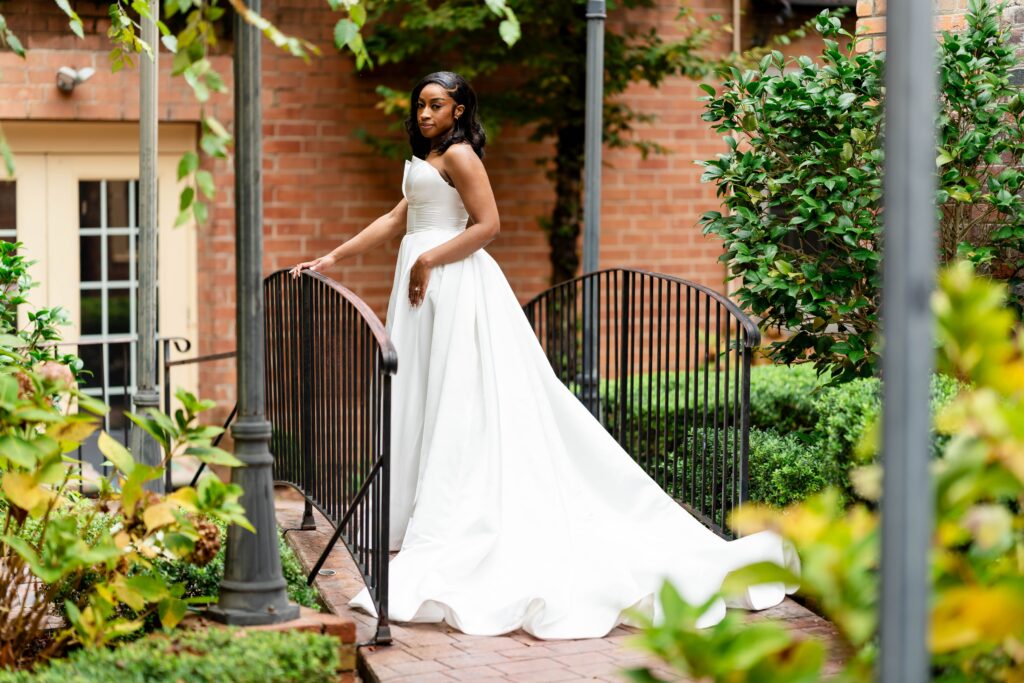 Beautiful Winston Salem bride posting for wedding day photos in the garden courtyard at The Event at Two Ten