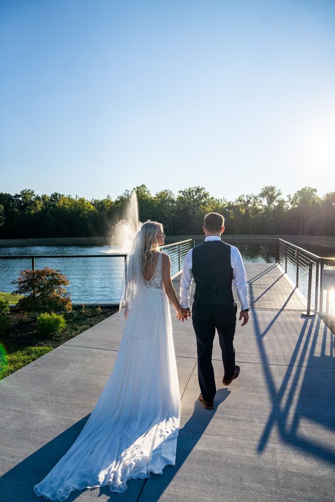 Bride & Groom enjoying a wedding day stroll on the pier with views of the pond & fountain at Hanover Reserve wedding venue on 45 private acres in Hamilton Ohio