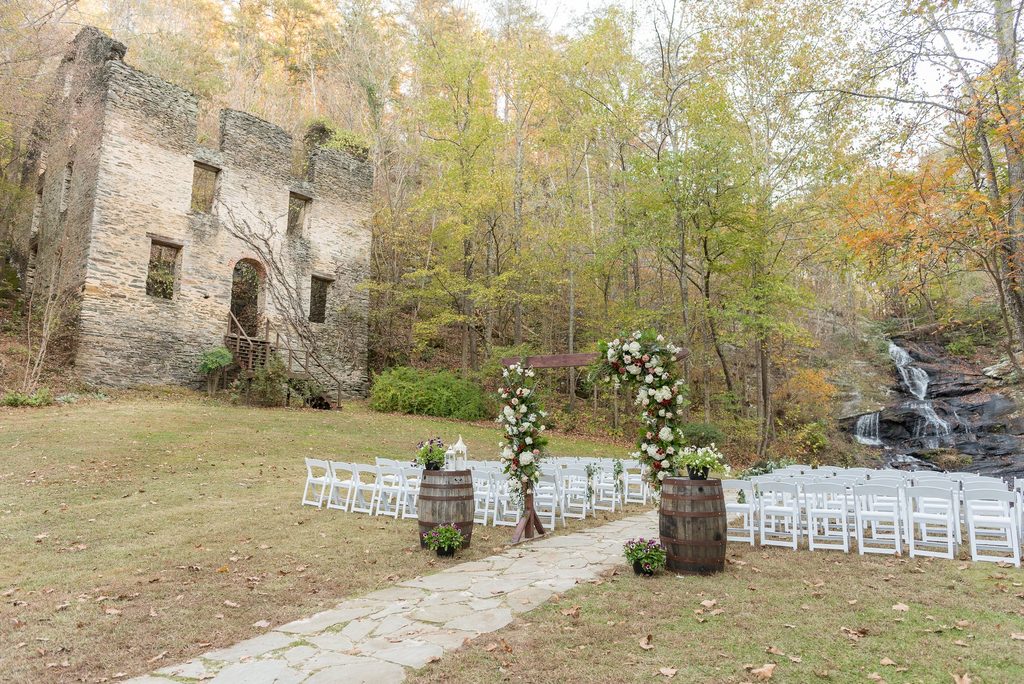 Outdoor garden wedding ceremony with historic ruins on one site and an 80 ft. waterfall backdrop surrounded by acres of forest views