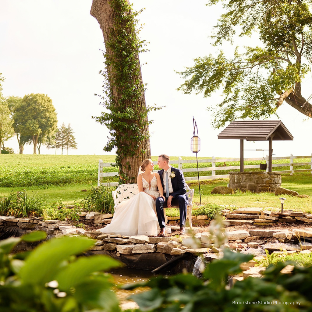 Bride and groom pose for spring wedding photos at the gardens, pond, fountain at Pole Barn Chic, an independently owned Springfield wedding venue