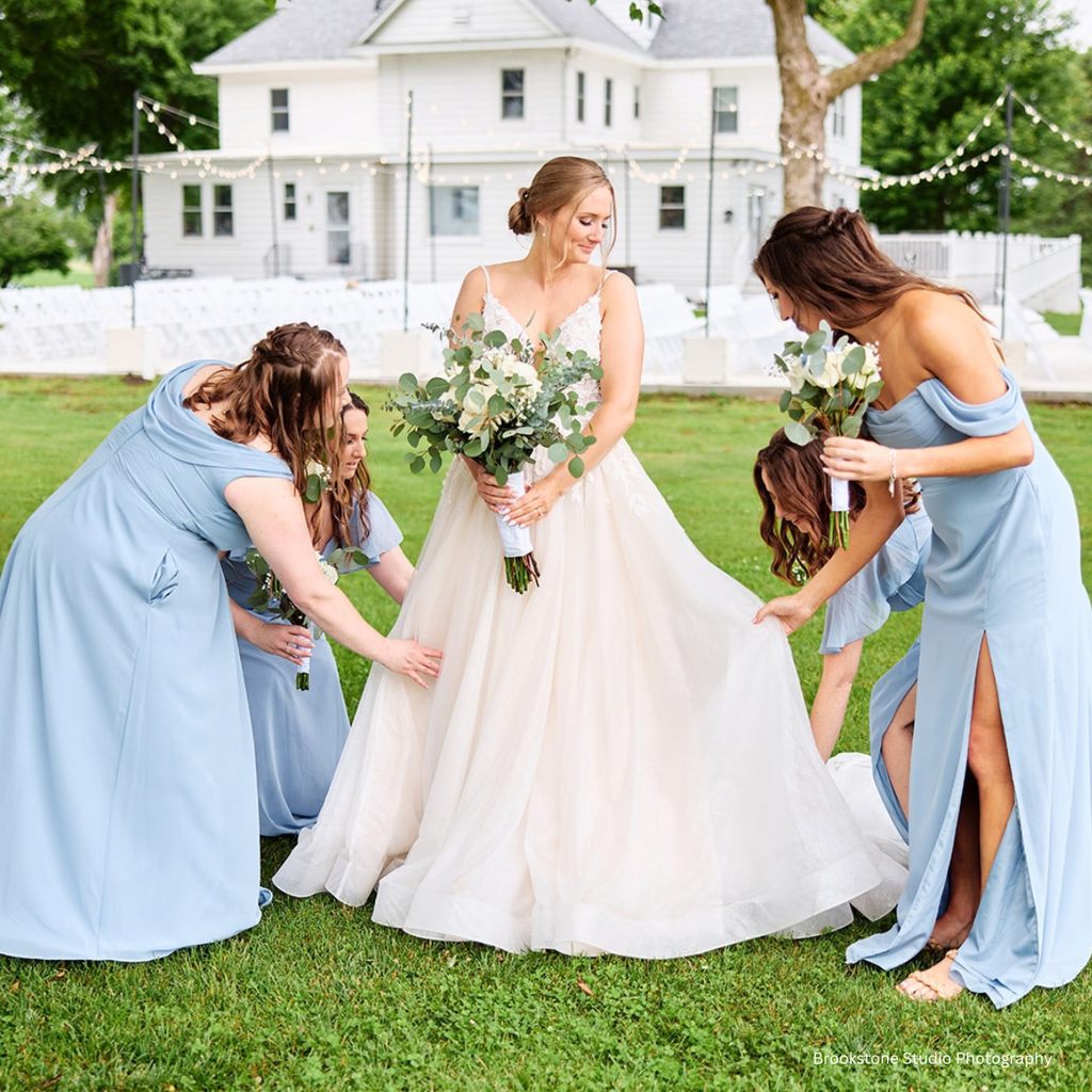 Bride and bridesmaids pose for wedding day photos in front of an outdoor garden ceremony & elegant historic manor house & white barn wedding venue surrounded by Central Illinois farmland in Springfield