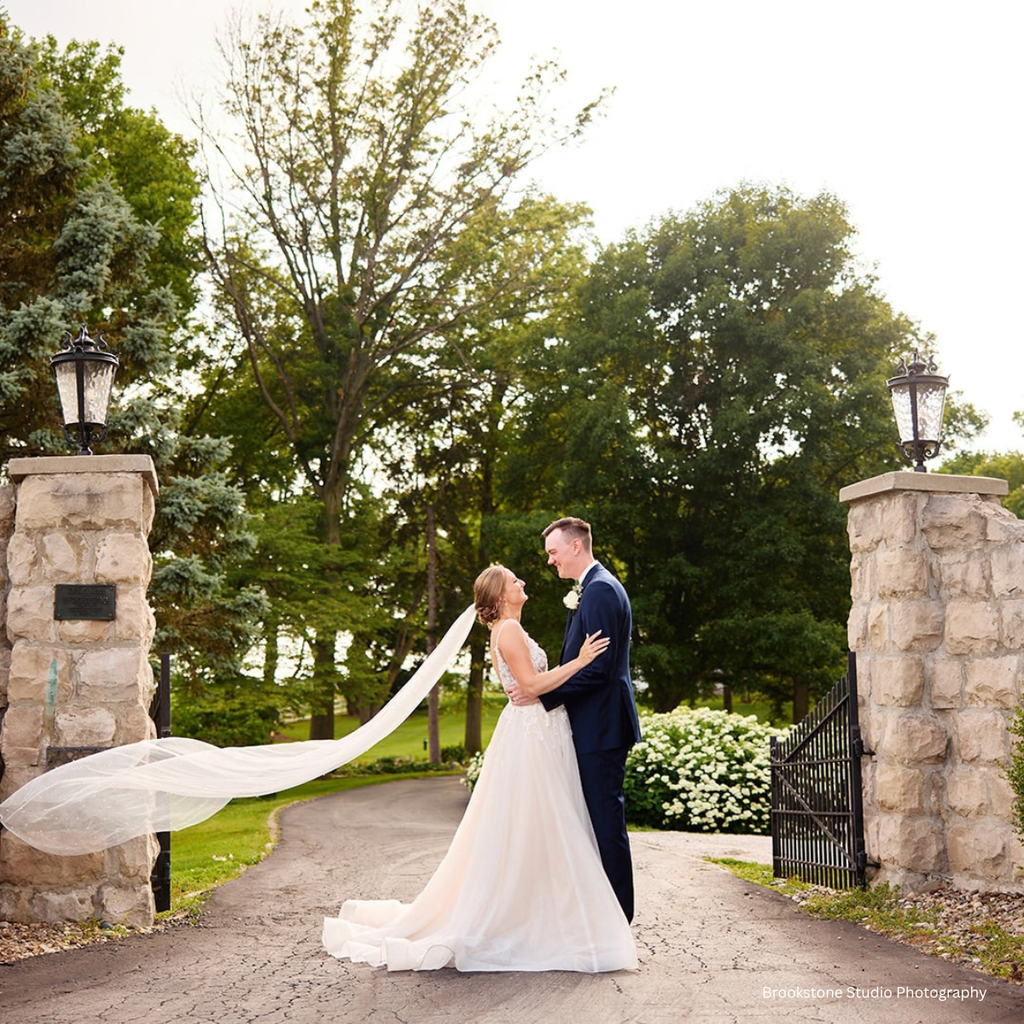 Bride & Groom posing for wedding day photos at the grand entrance gates at Pole Barn Chic a Central Illinois country elegance wedding venue only about an hour a half from St. Louis
